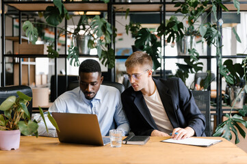 Multiracial colleagues using laptop together