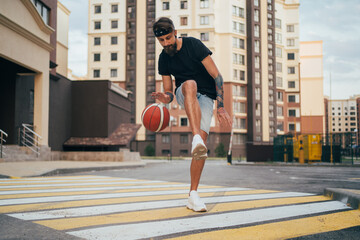 Urban activity: young man playing basketball on the street