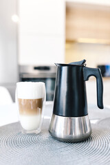 Cup of coffee on table and coffee maker