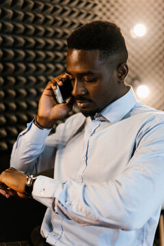 Ethnic businessman checking time during phone call