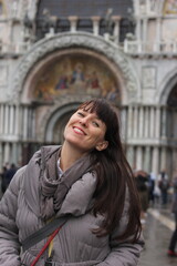 Smiling woman in casual casual clothes against blurred background of San Marco cathedral in Venice, Italy