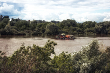 Fototapeta premium Floating raft with camping tents on river with beautiful countryside scenery 