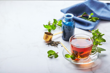 Black tea in glass transparent mug with mint leaves. Soothing tea, anti-stress