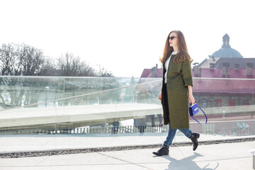 Girl with long blonde hair in a long green walking around the city, spring weather