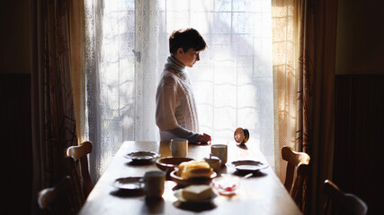 Fototapeta na wymiar Poor sad small girl setting table indoors at home, poverty concept.