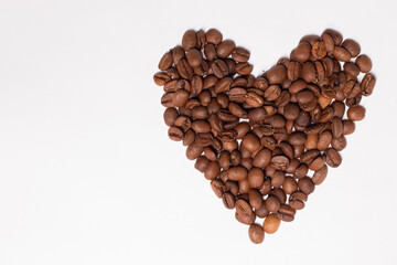 Freshly roasted coffee beans in shape of a heart isolated on white background. top view