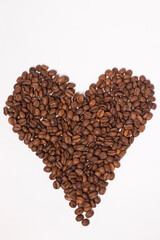 Freshly roasted coffee beans in shape of a heart isolated on white background. top view