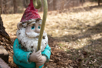 Gnome, lawn ornament, white beard blue eyes, ceramic, weathered, paint chipping, gold yellow staff, red hat, white, turquoise blue jacket, cute, friendly looking, garden gnome, outdoor decoration