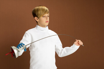 Boy fencer in white fencing costume with rapier