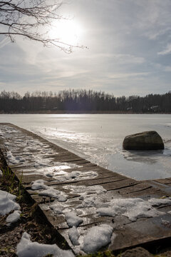 Old wooden bridge on the frozen lake. Polish winter landscape. Selective focus. 
