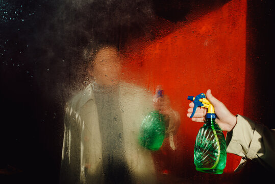 Reflection in the mirror of a person washing the mirror