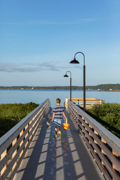 Young Child walking to Maine beach on Boardwalk with Fishing Net