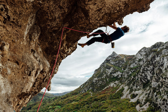 Young climber man climbing a steep overhanging rock