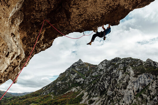 Young climber man climbing a steep overhanging wall
