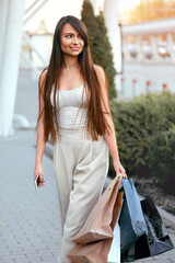 Young woman with shopping bags walking out from shop