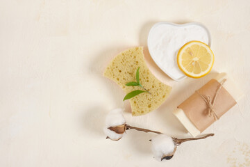 sponge, soap, lemon and soda on beige backgrund top vire copy space, green leaves and saucer with baking soda