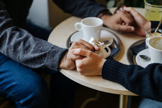 Heterosexual couple holding hands over a coffe table.
