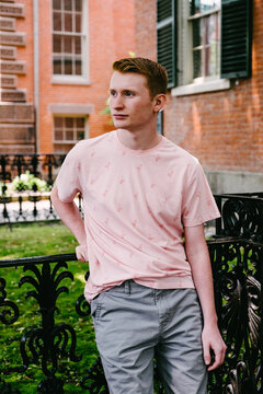 red head teenage boy standing and leaning on fence