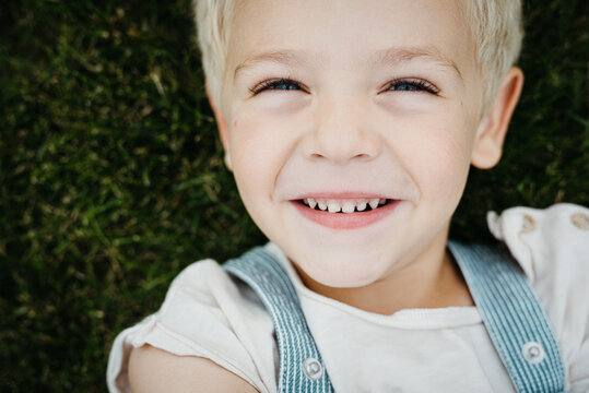 sweet blond toddler boy laying on the grass outdoors
