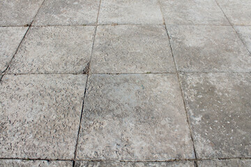Fototapeta premium Old large square concrete paving slabs. Sidewalk. Perspective. Selective focus. Background. Texture.