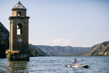 Anonymous traveler riding boat near tower