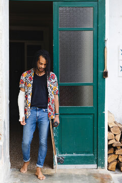 Young man with bandaged arm and skateboard in his hand