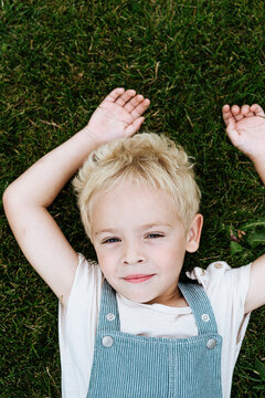 sweet blond toddler boy lying on the grass outdoors