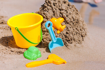 Fototapeta na wymiar Child's bucket, spade and other toys on tropical beach against blue sky