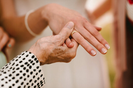 close up of grandma holding hand of bride with golden wedding ring