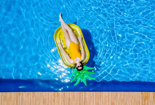 Teenager relaxing on pineapple floating in pool