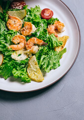 Fresh salad with shrimp, tomatoes and parmesan cheese in a plate, close-up. Healthy food