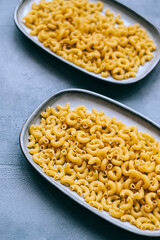 Wheat raw Italian pasta in plates isolated on blue background.