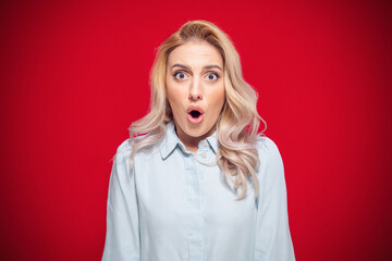 Surprised face of woman stare to camera, isolated on red background. Surprise expression face -...
