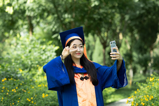 A Smiling Female Graduate is Using Mobile Phone