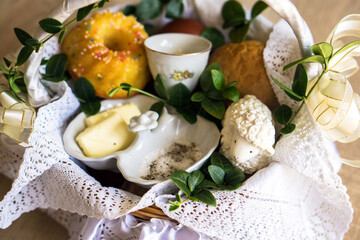 Preparation of a festive Easter Basket. Traditional Blessing of the Easter Food Baskets. Traditions on Holy Saturday. Horseradish, butter, bread, buxus, sausage, muffin, painted eggs and Sugar lamb.