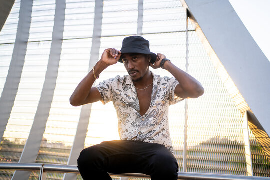 Young Black Man Putting On A Hat At Sunset.