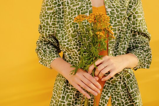 Crop woman holding yellow flowers