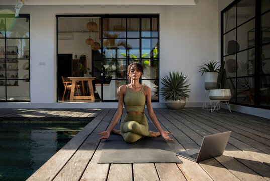 Woman following yoga program on laptop and dedicatedly following