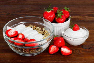 bowl of oat granola with yogurt, fresh strawberry on wooden background for healthy breakfast with copy space.