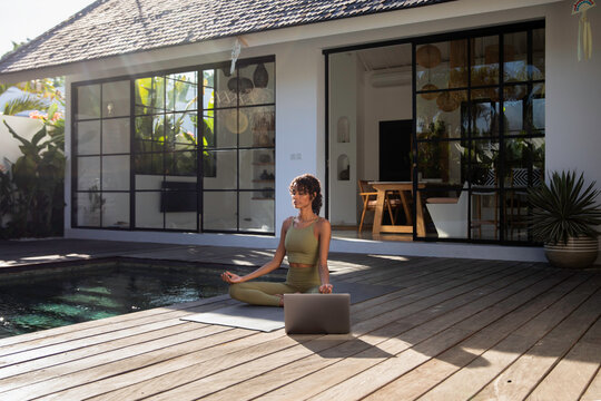 Woman following yoga program on laptop and dedicatedly following