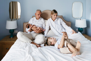 Beautiful family with small children in a cozy bedroom.