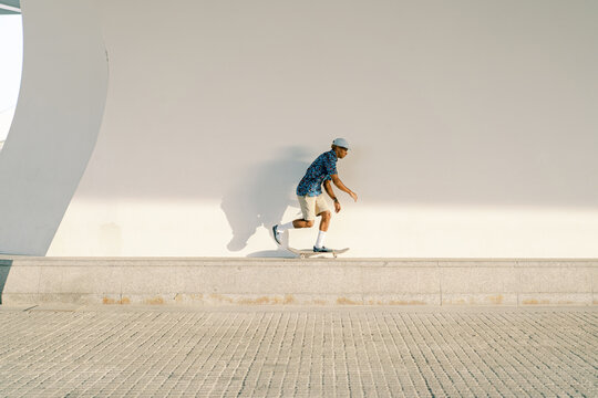 Ethnic skater riding skateboard on border