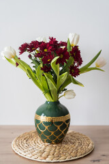 Bouquet of tulips and chrysanthemums in a vase on a white background.