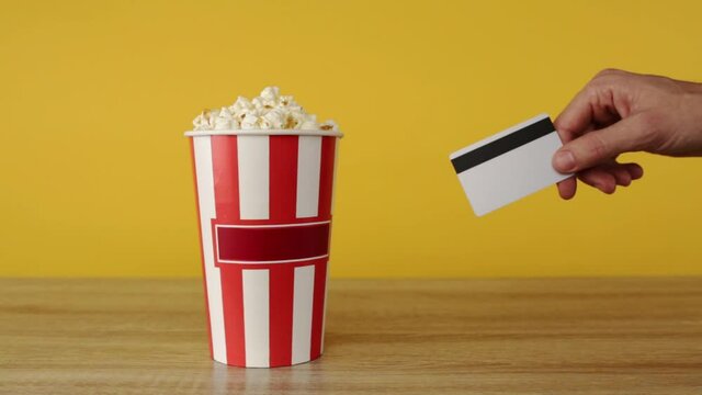 Hand holding a credit card, buying popcorn at the cinema