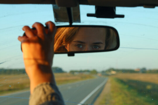 Female driver adjusting rear view mirror