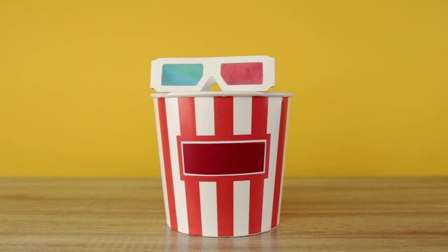 Hand puts 3d glasses on buckets with popcorn