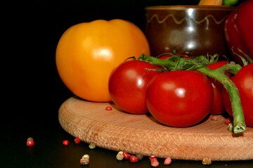 Close up of red and yellow tomatoes on wooden board. Black background