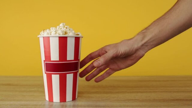 Hand takes buckets with popcorn