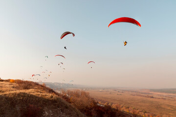Paragliders fly in autumn over hills