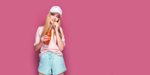 Sporty woman with cold drink standing on pink background